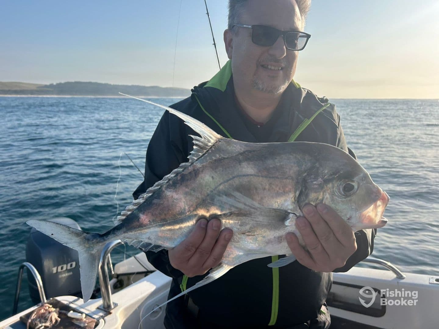 Angler proudly displaying a large fish while fishing on a boat in calm waters, showcasing a successful catch during a day out.