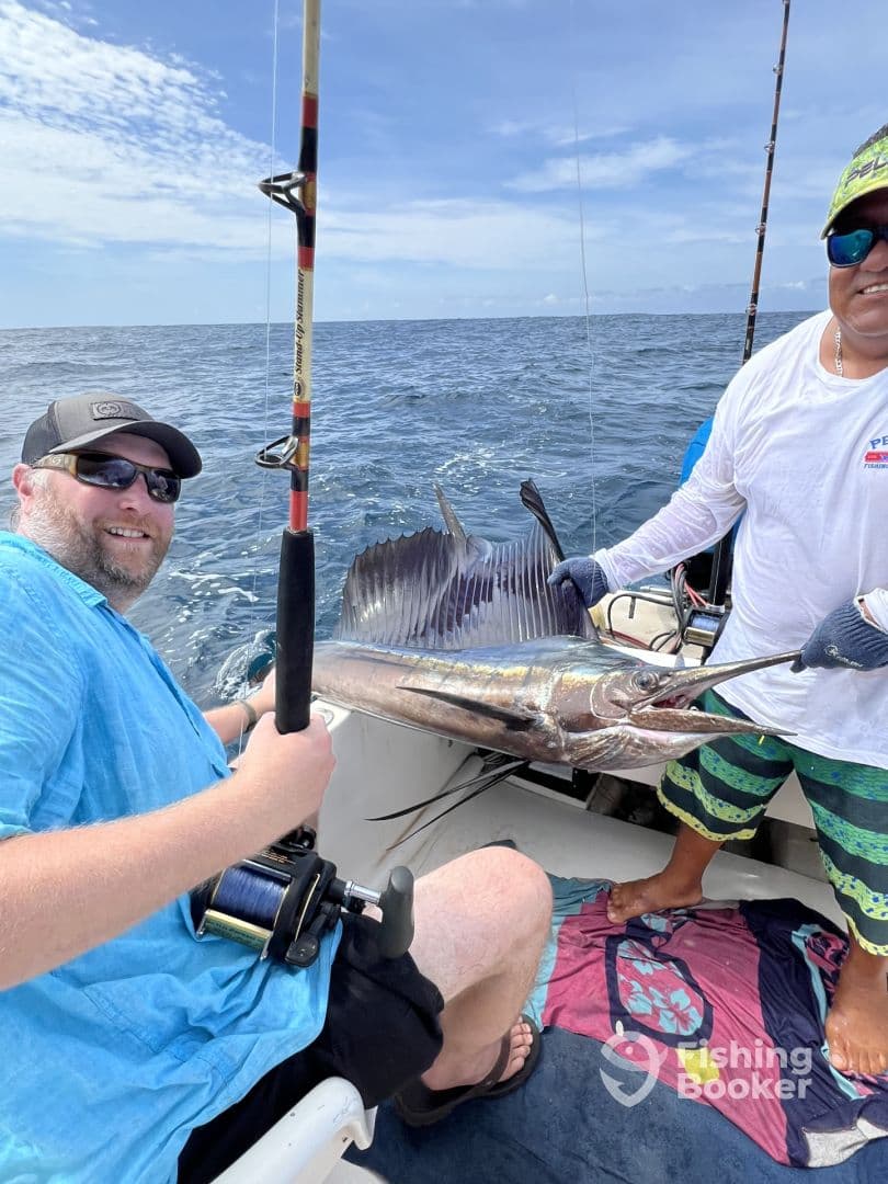 Two anglers proudly displaying a large Sailfish while fishing offshore, showcasing the excitement of deep-sea fishing.