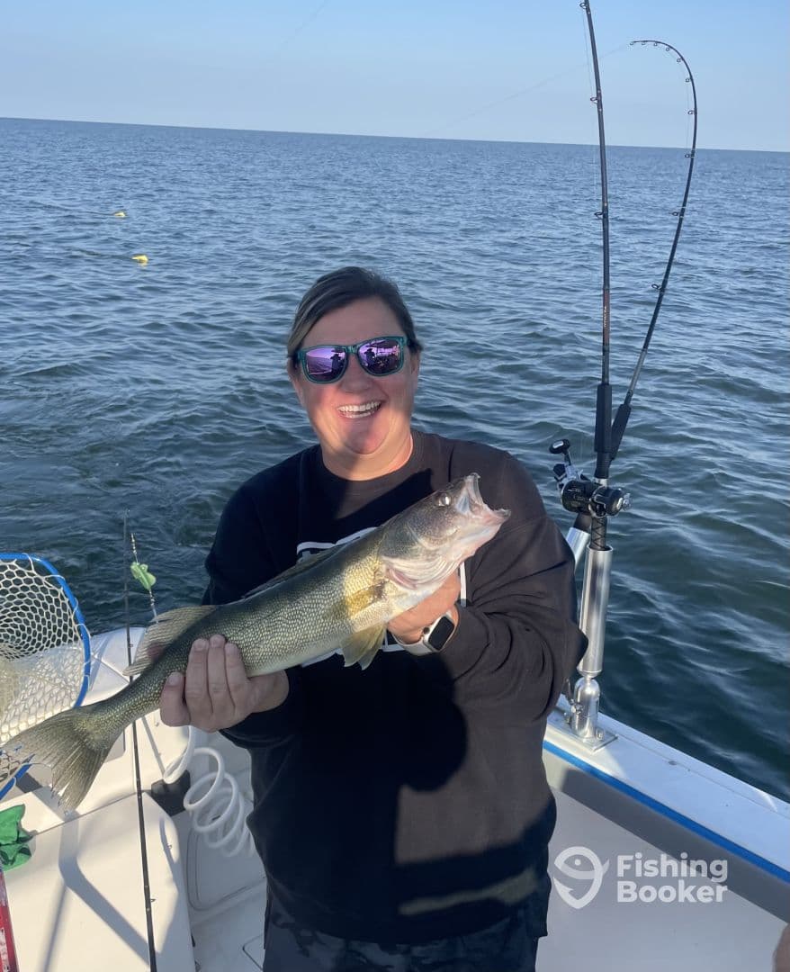 Angler proudly displaying a Walleye while fishing on a boat in open waters.