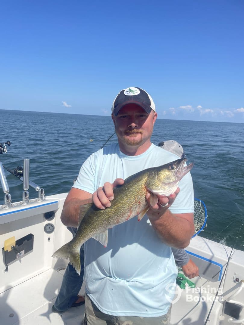 An angler proudly displaying a Walleye while fishing on a boat in open water.