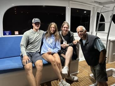 A group of four enjoying the comfortable seating inside a modern fishing boat, showcasing a cozy atmosphere for night fishing adventures.