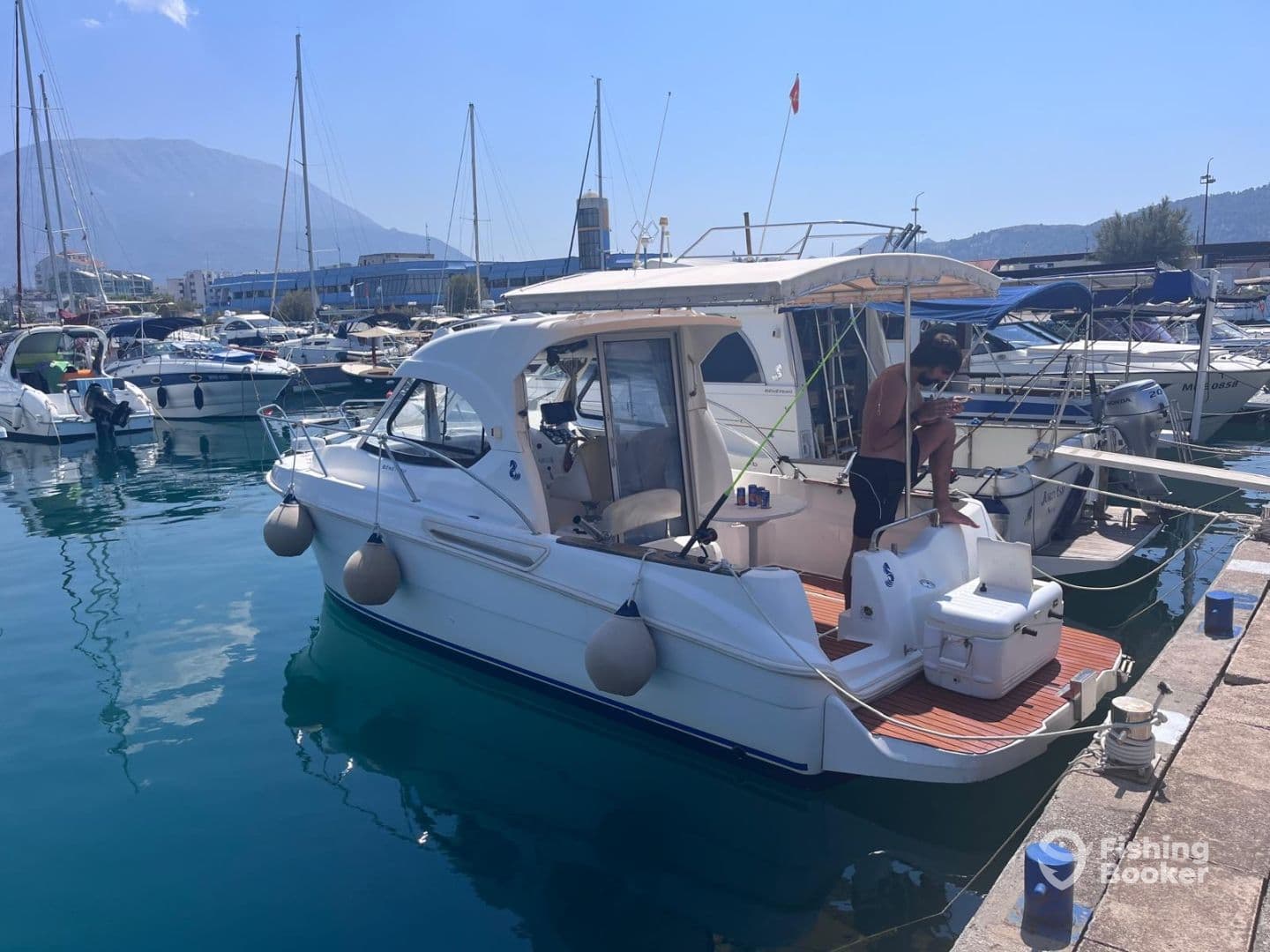 A sleek motorboat docked in a marina, showcasing its exterior design and surroundings, with a person seated on the boat.