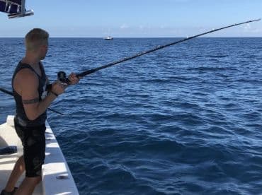 An angler casting a line from a boat into the open ocean, showcasing the excitement of deep-sea fishing.