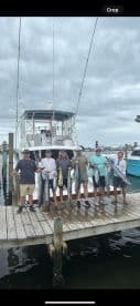 A group of anglers proudly displaying their catch of Mahi Mahi and King Mackerel on the dock after a successful fishing trip.