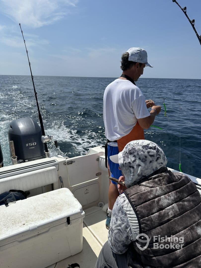 Two anglers preparing their gear on a boat while fishing in open waters, showcasing a typical offshore fishing environment.
