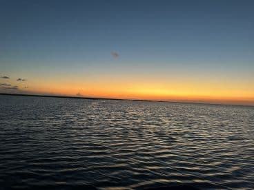 A serene sunset over calm waters, capturing the tranquil beauty of the fishing environment.