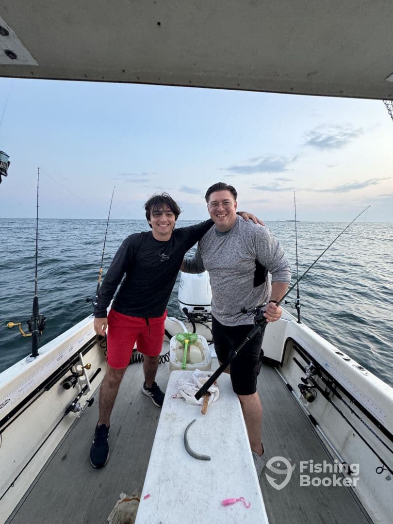 Two anglers enjoying a fishing trip on a boat, posing together with fishing rods in hand against a scenic ocean backdrop.