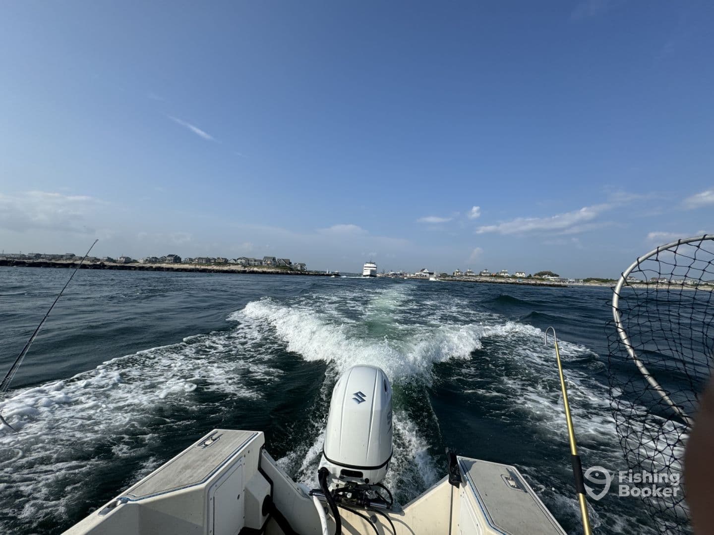 A scenic view from the back of a boat, showcasing the wake and coastal scenery as it heads out for a fishing adventure.