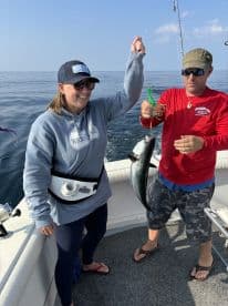 Angler proudly displaying a caught fish while fishing on a boat in open waters.