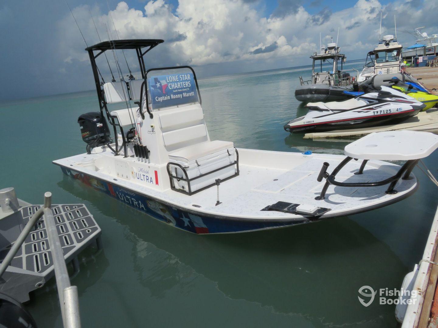 A sleek fishing boat named 'Ultra' docked at a marina, showcasing its spacious layout and fishing gear setup.