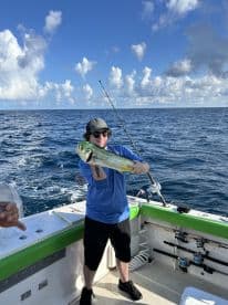 Angler proudly displaying a vibrant Mahi Mahi while fishing offshore, showcasing a beautiful day on the water.
