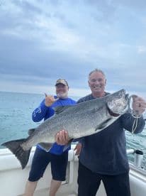 Two anglers proudly displaying a large Lake Trout caught during a fishing trip on the open water.