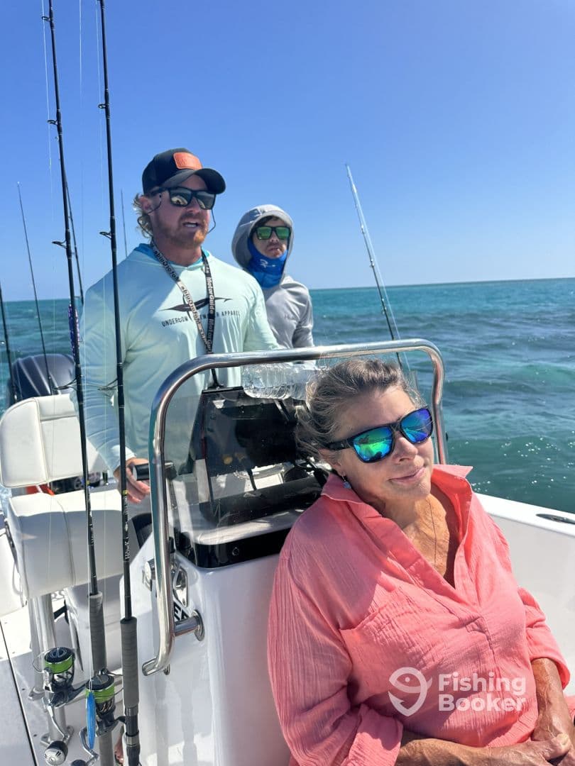 A group of anglers enjoying a day on the water, with one person seated at the helm and two others in the background, showcasing a comfortable boat interior.