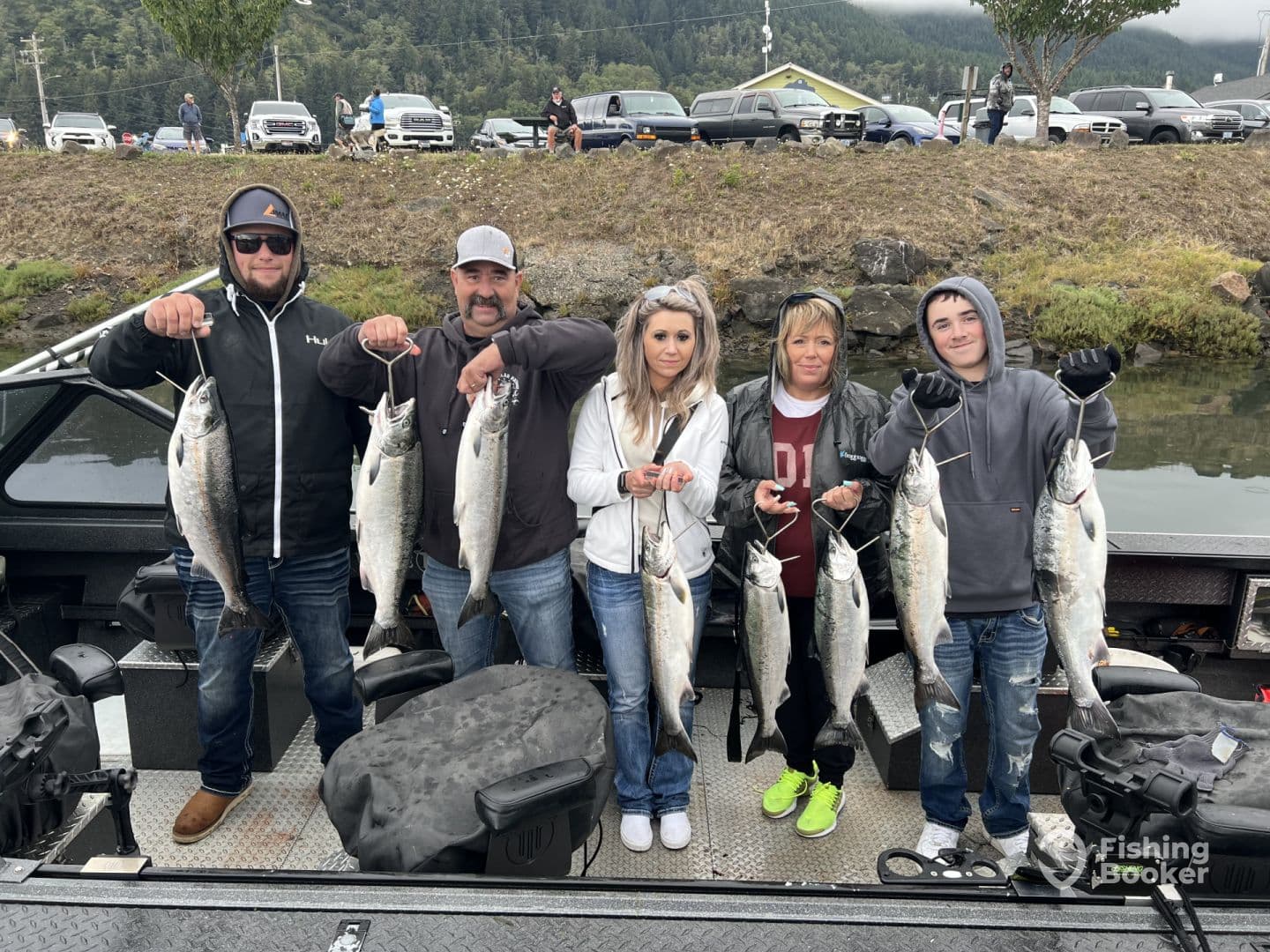 A group of anglers proudly displaying their catch of several Silver Salmon while aboard a fishing boat, showcasing a successful day on the water.