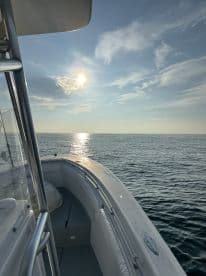 A scenic view of the boat's exterior with the sun setting over calm waters, showcasing a peaceful fishing environment.