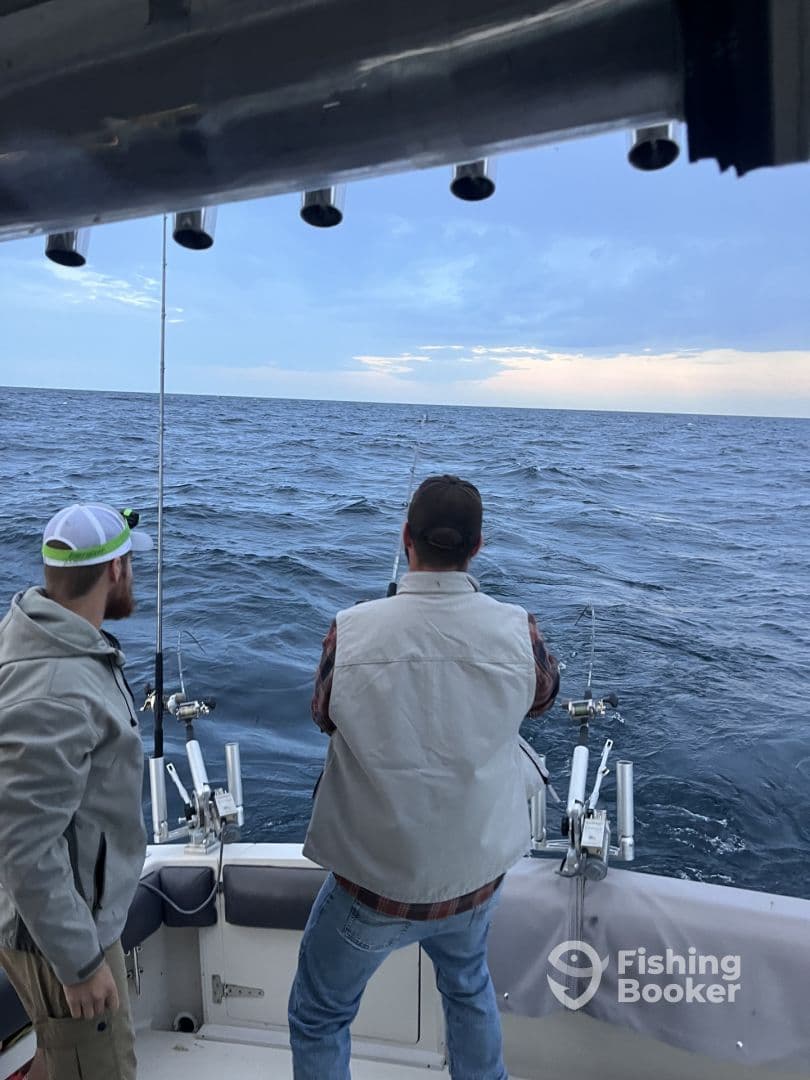 Two anglers actively fishing on a boat, with rods in hand, enjoying a day on the open water.