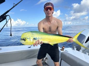 Angler proudly displaying a vibrant Mahi Mahi while fishing offshore, showcasing the excitement of a successful day on the water.