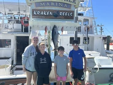 A group of young anglers proudly posing with their catch at Kraken Reels Marina, showcasing a successful fishing trip.