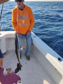 An angler proudly displaying a caught fish while aboard a fishing boat, enjoying a day on the open water.