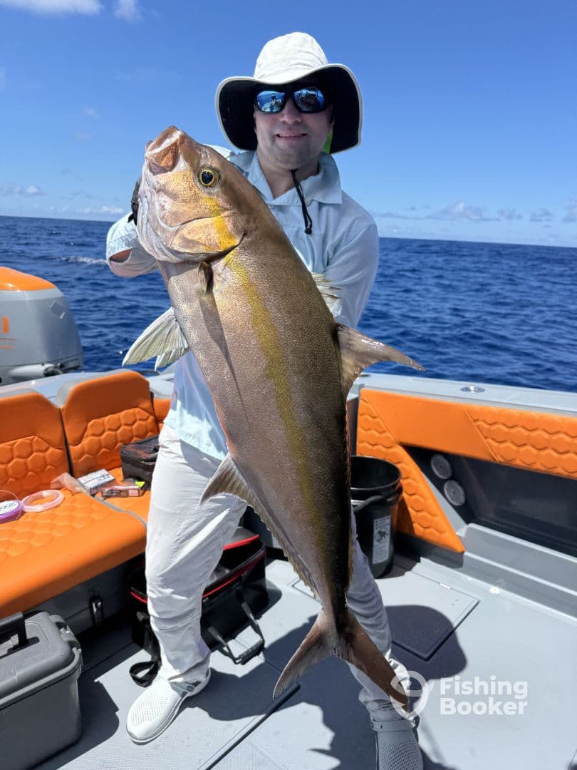 An angler proudly displaying a large Amberjack while fishing on a vibrant boat in open waters.