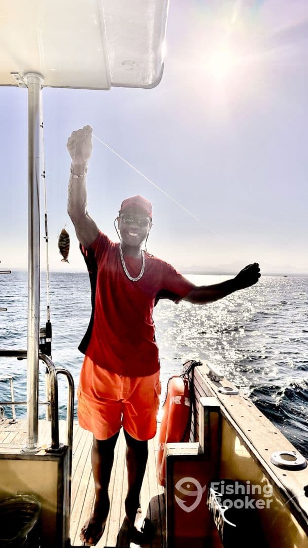 Angler proudly displaying a small fish while fishing on a sunny day, showcasing the excitement of the catch.