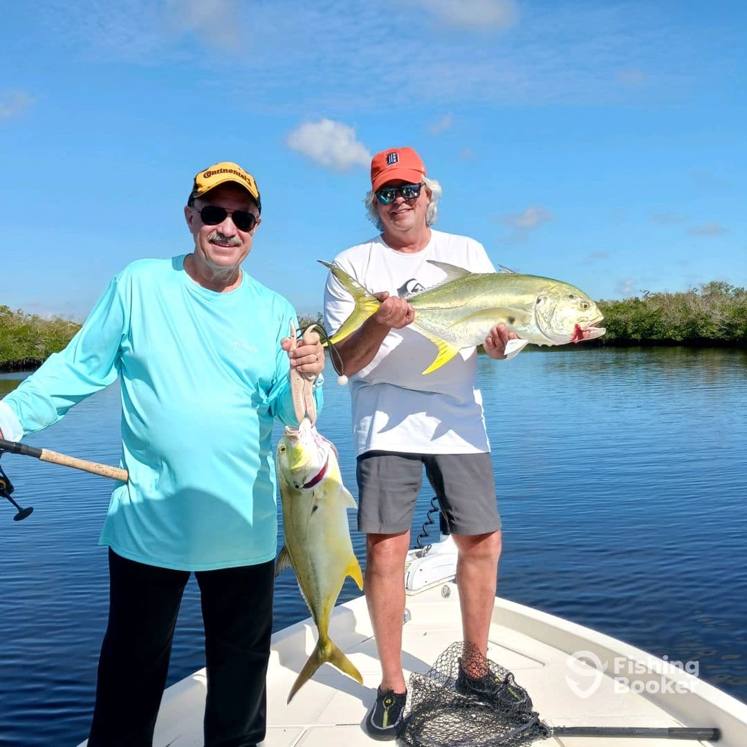 Two anglers proudly displaying their catches of Yellowtail Snapper while fishing in a serene coastal environment.