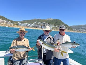 Three anglers proudly displaying their catches of Yellowtail while enjoying a sunny day on the water.