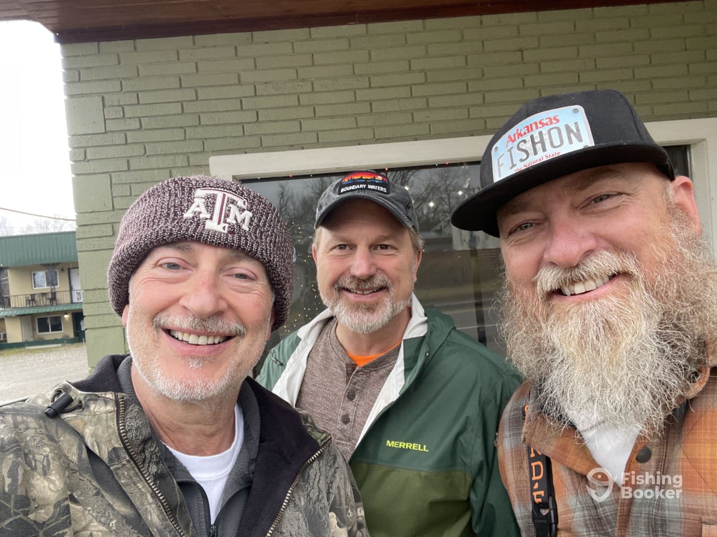 Three anglers smiling for a selfie outside a fishing lodge, showcasing camaraderie before their fishing adventure.