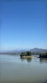 A scenic view of a calm water body surrounded by mountains, ideal for fishing but lacking any visible fishing activity.
