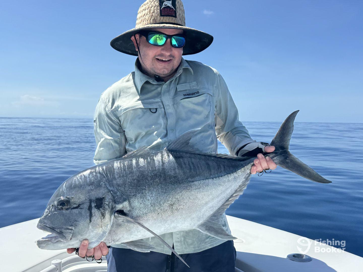 Angler proudly displaying a large Grey Snapper while fishing in open waters.
