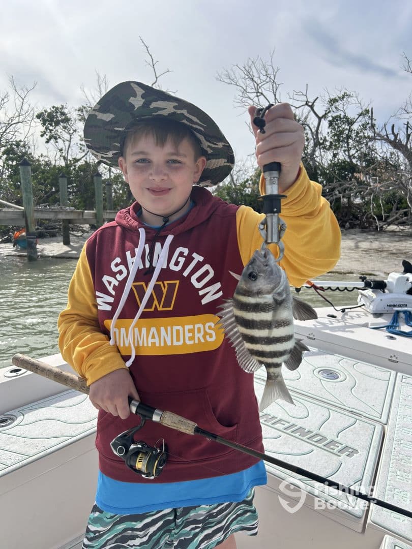 A young angler proudly displaying a striped fish while fishing from a boat, showcasing a fun day on the water.
