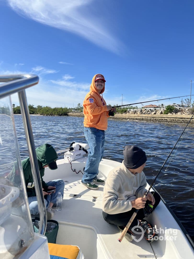 A group of anglers enjoying a fishing trip on a boat, with one person actively casting while others prepare their gear.