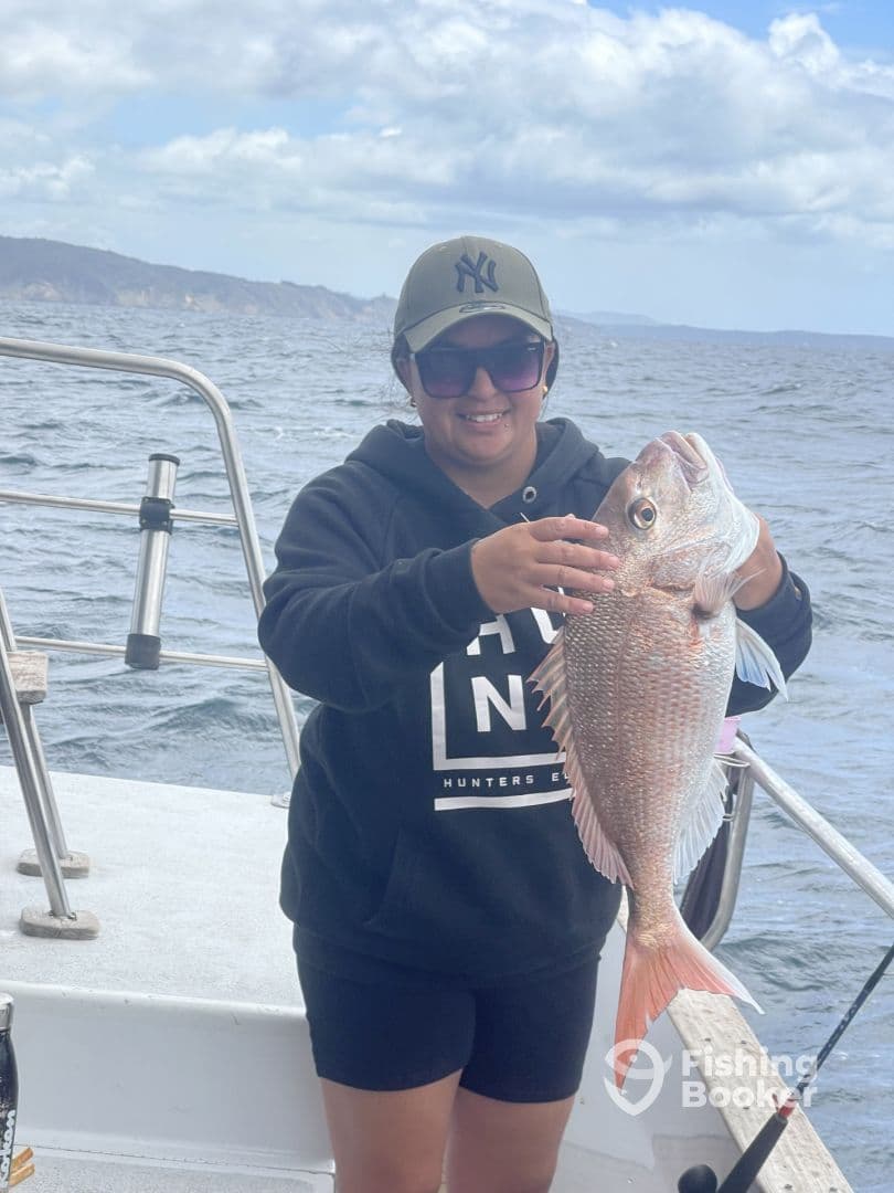 Angler proudly displaying a large Snapper while fishing on a boat in open waters.