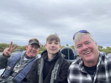 A family enjoying a fishing trip, seated inside a boat with a scenic backdrop, showcasing a relaxed atmosphere.