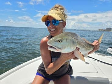 Angler proudly displaying a Redfish while enjoying a sunny day on the water.