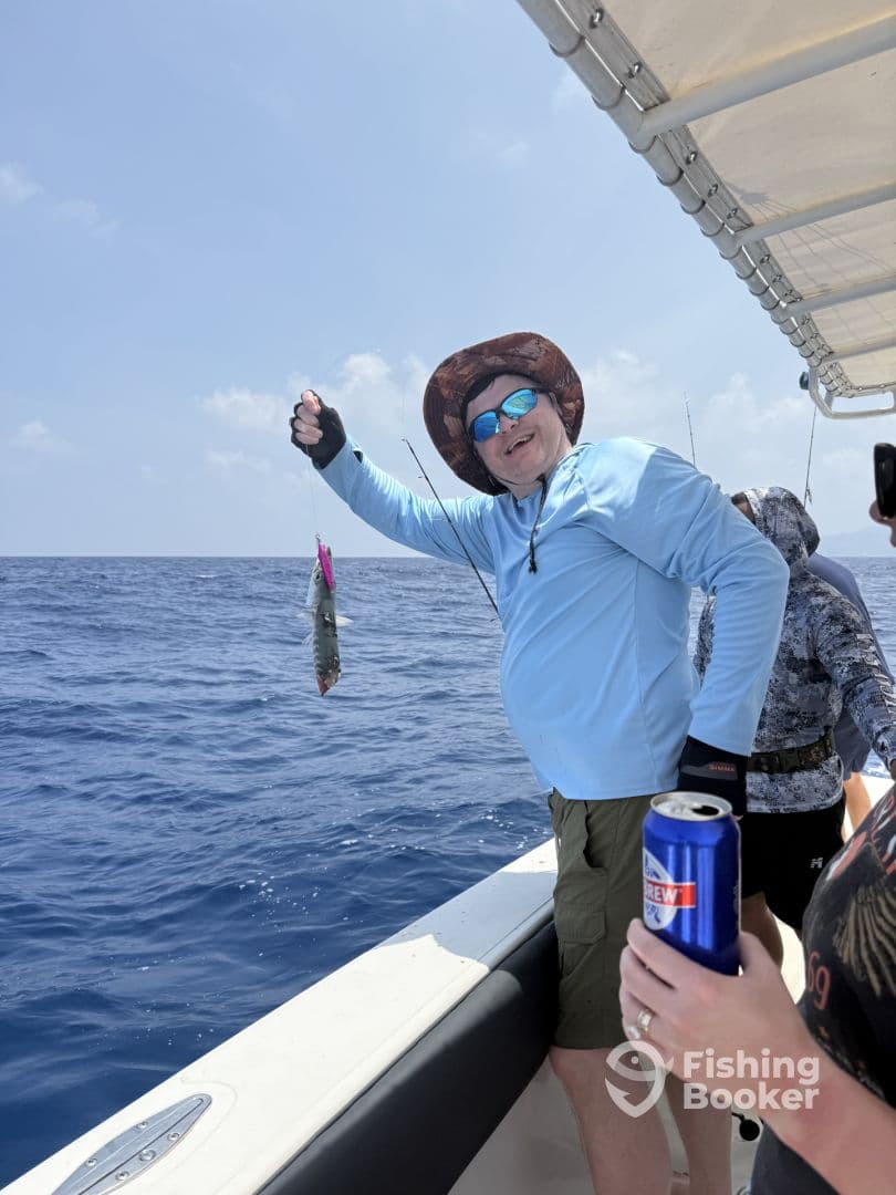 Angler proudly displaying a fish while fishing on a boat in open waters, enjoying a sunny day at sea.