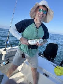 An angler proudly displaying a freshly caught fish while aboard a fishing boat in open waters.