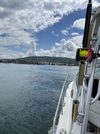 A scenic view of a boat navigating through calm waters, showcasing the coastline and a clear blue sky.