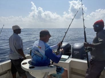 Three anglers actively fishing on a boat, with rods in hand, enjoying a day on the open water.