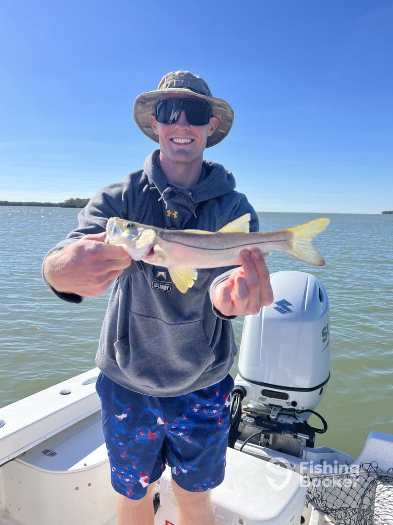 An angler proudly displaying a Snook caught while fishing on a sunny day in a coastal waterway.