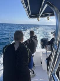 Group of anglers on a boat, actively engaged in fishing with rods in hand, enjoying a sunny day on the open water.