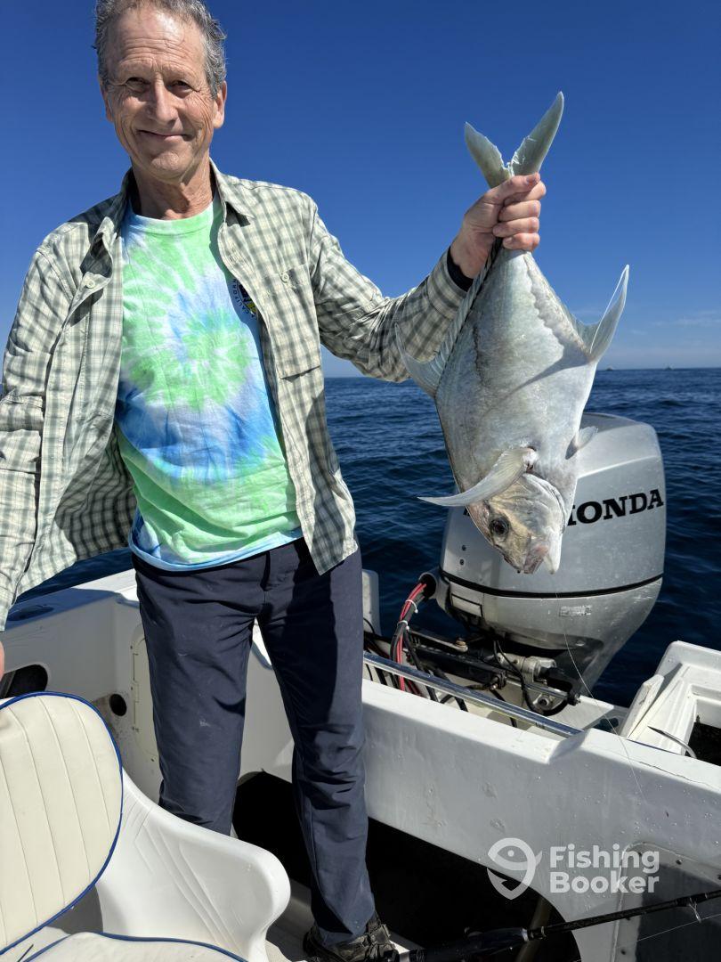 An angler proudly displaying a large fish on a boat, enjoying a day of fishing in open waters.