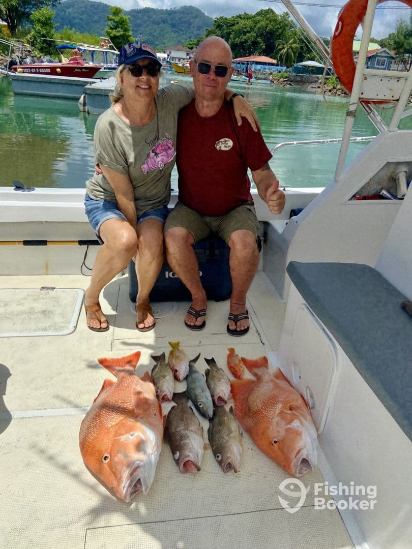 Two anglers proudly displaying their catch of Snapper and Grouper on a boat after a successful fishing trip.