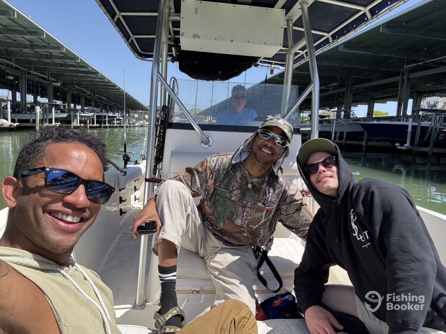 Three friends enjoying a sunny day on a fishing boat, showcasing a relaxed atmosphere before heading out on the water.