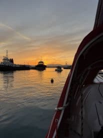 A picturesque sunset view over the harbor, showcasing various boats docked as the day comes to a close.