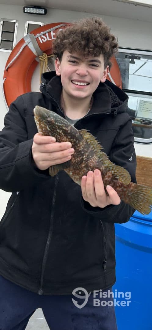 A young angler proudly displaying a large Rockfish aboard a fishing charter, showcasing the excitement of a successful catch.
