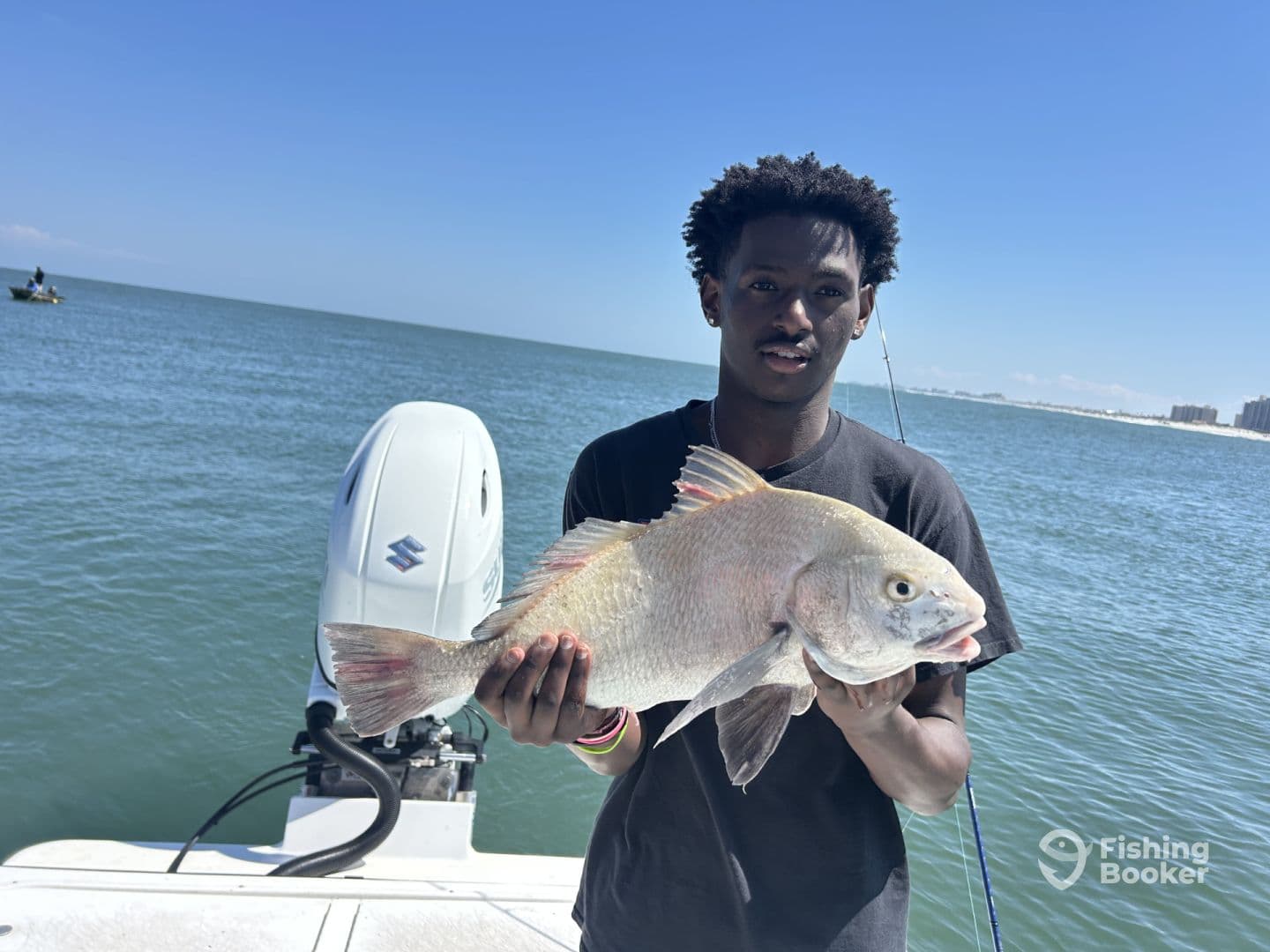 Young angler proudly holding a large Snapper while fishing off the coast, showcasing a successful day on the water.