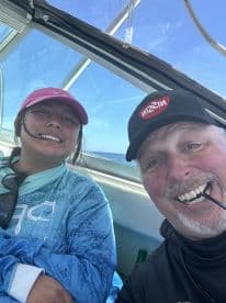 Two anglers enjoying a moment inside the boat, showcasing a relaxed atmosphere during their fishing trip.