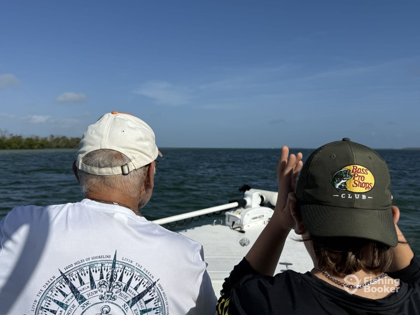 A young angler and an adult enjoying a day on the water, seated in the boat while observing the scenic view.
