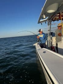 Angler reeling in a catch while fishing on a boat, showcasing an active fishing environment.